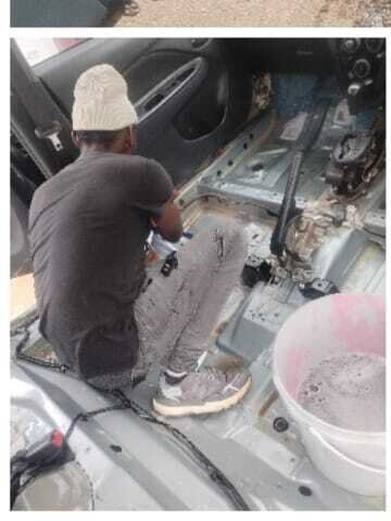 Worker scrubbing stripped car interior floor during full valet deep clean.