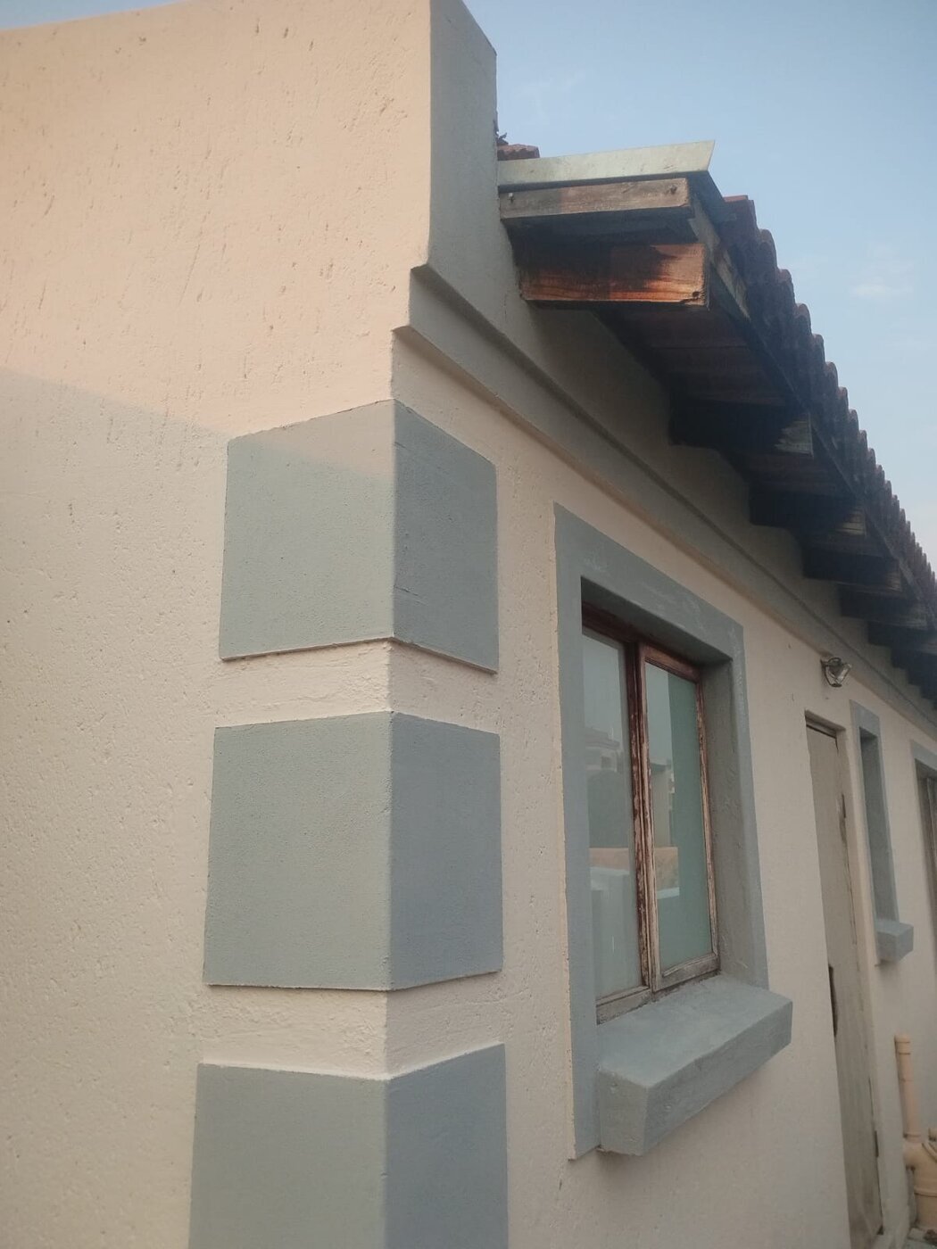 Fresh cream and grey exterior paint on a residential corner and window frame.